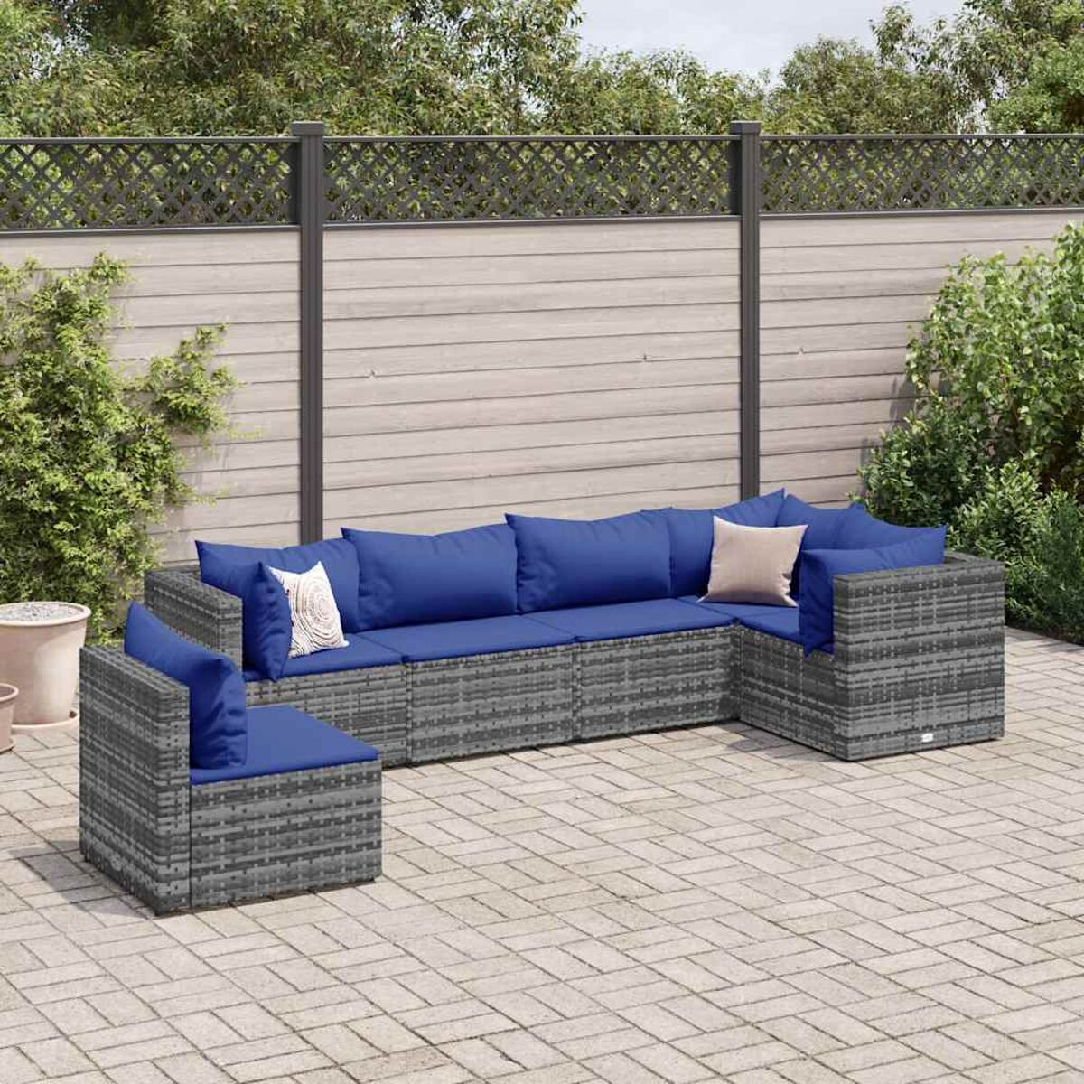Graues Outdoor-Ecksofa mit blauen Kissen. Ziegel-Patio und Holzzaun.