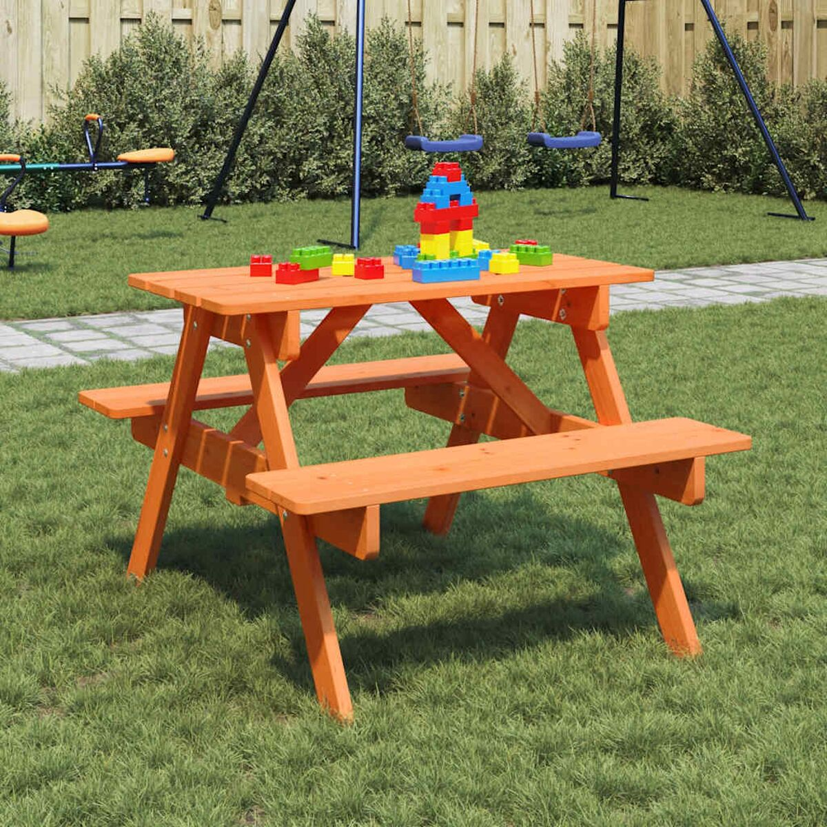 Tavolo da picnic arancione con panche sull'erba. Giocattoli sul tavolo.