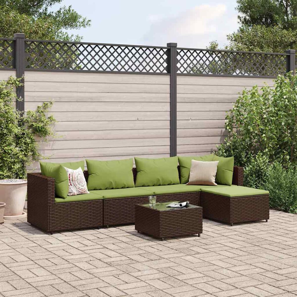 Set divano in rattan da esterno con cuscini verdi e tavolino.