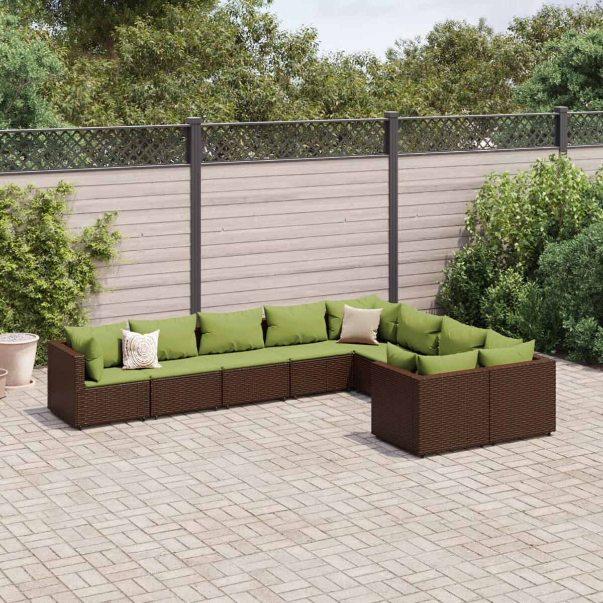 Outdoor-Korbsessel-Set mit grünen Kissen auf einer Backstein-Terrasse.