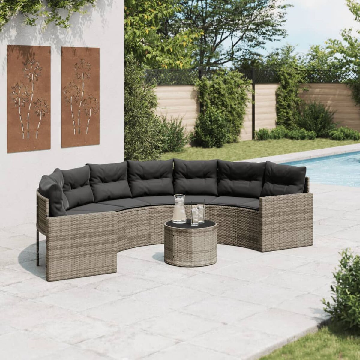 Outdoor-Sitzbereich mit geschwungenem, grauem Korbsofa, rundem Tisch und Pool.