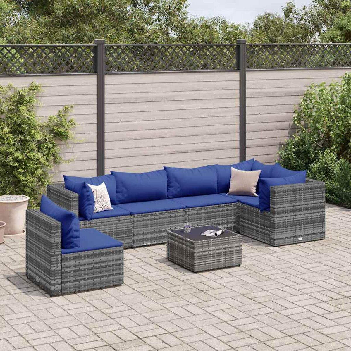 Rattan-Sofa-Set für den Außenbereich mit blauen Kissen und Beistelltisch.