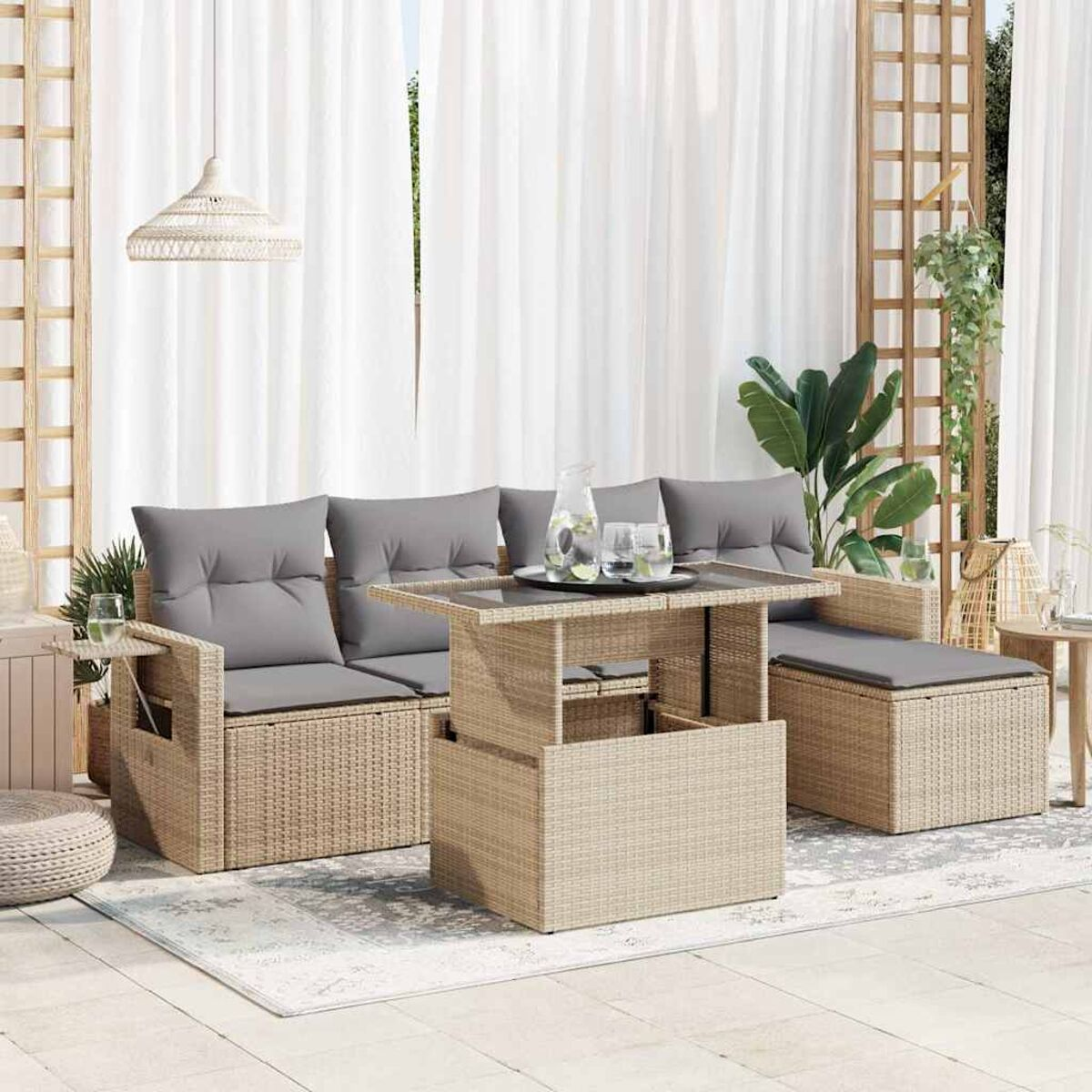 Set divano da esterno in vimini beige con tavolino e cuscini grigi.