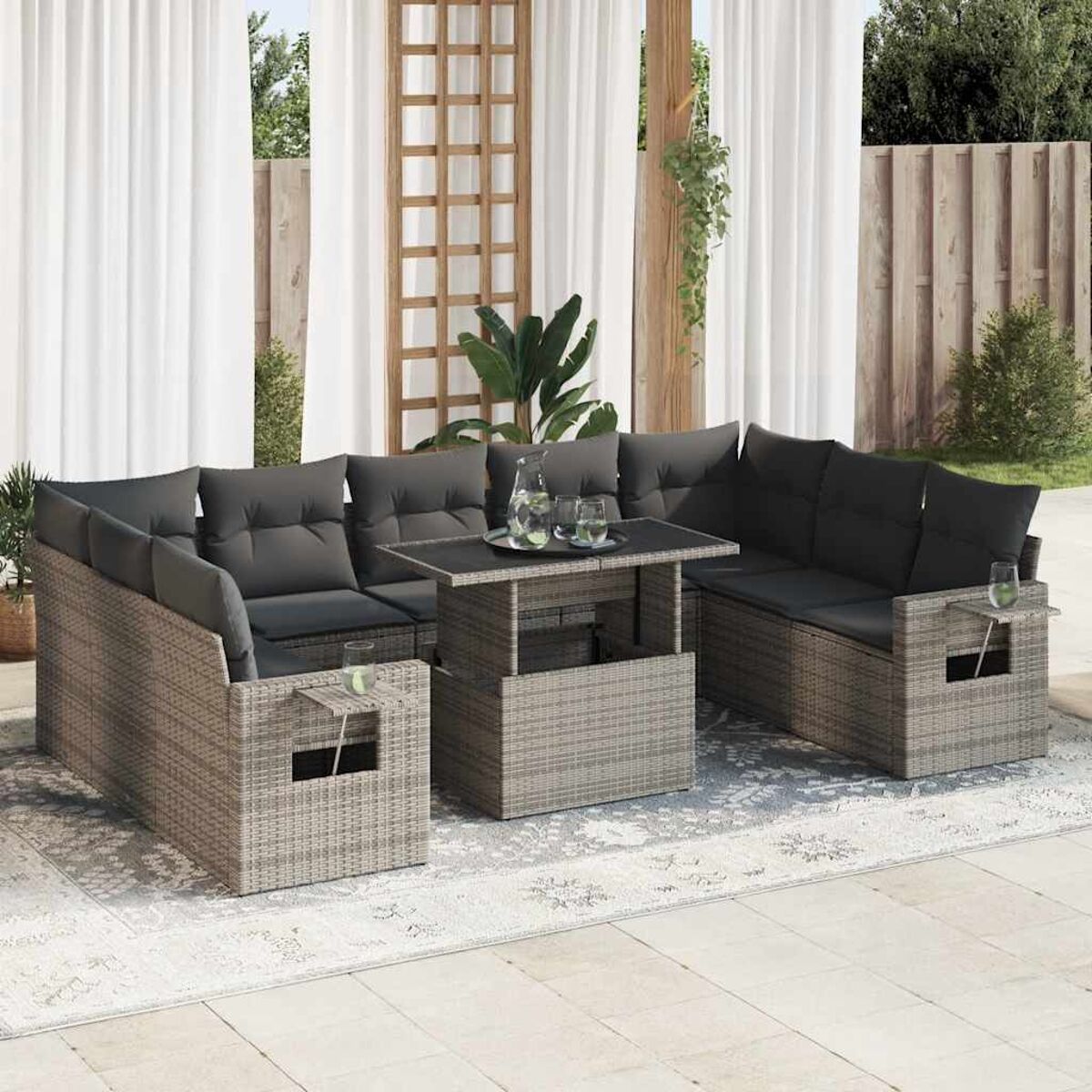 Set di mobili da esterno in rattan grigio. Include un divano componibile e un tavolo quadrato con piano rialzabile. Bicchieri sul tavolo.
