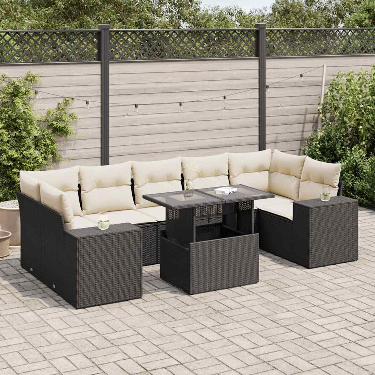 Schwarze Outdoor-Korbmöbel mit beigen Kissen und einem Tisch auf einer Terrasse.