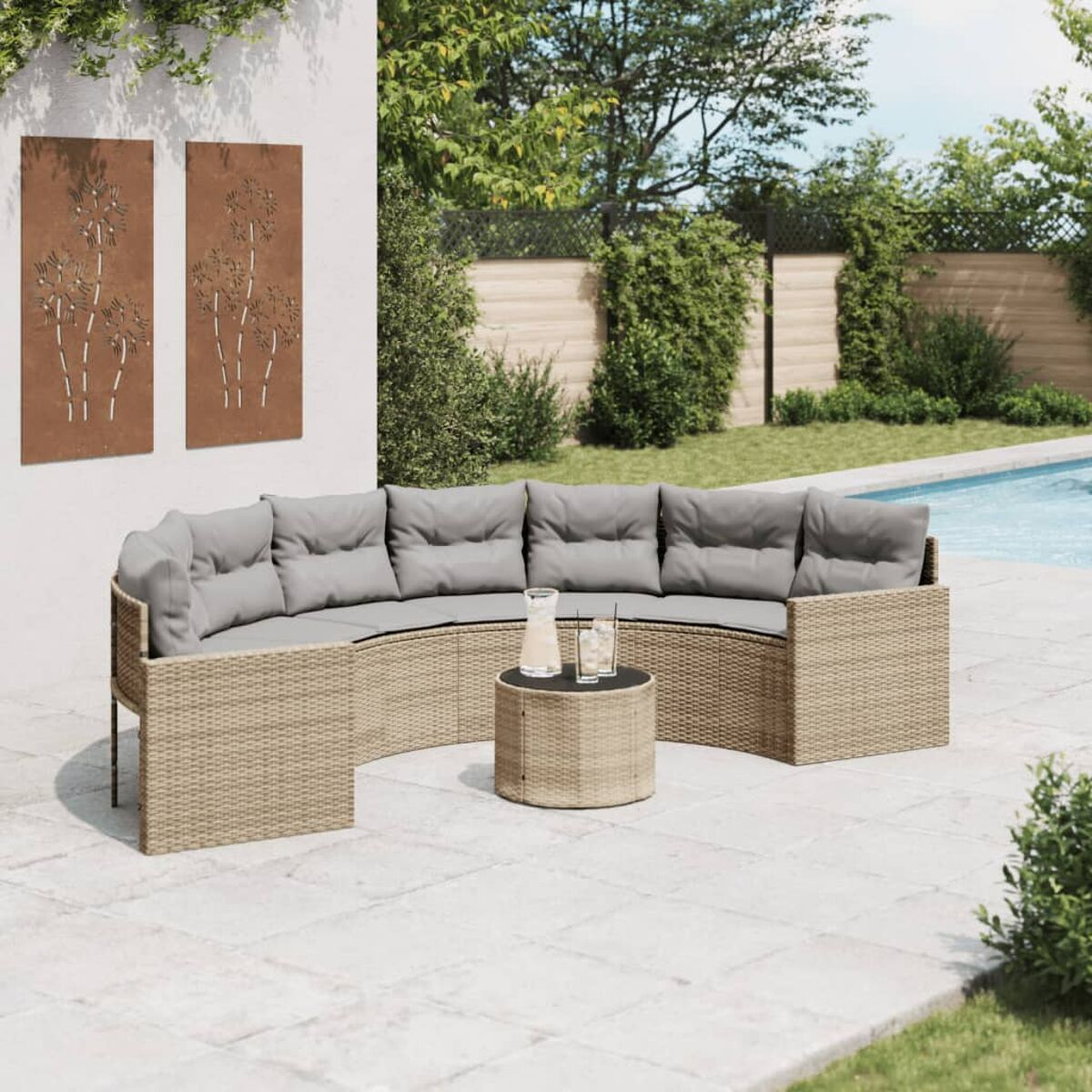 Un divano curvo in vimini con cuscini grigi su un patio con piscina.