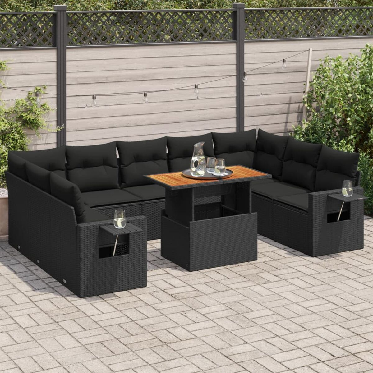 Divano componibile nero per esterni con tavolo con sollevamento. La scena è ambientata su un patio pavimentato.