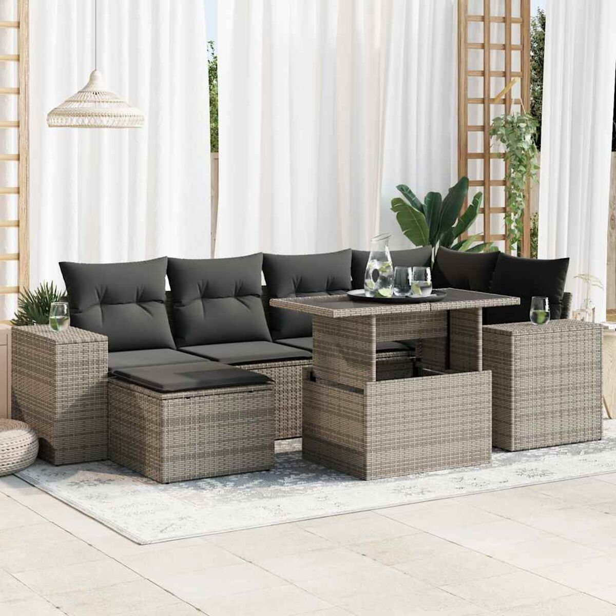 Eine graue Outdoor-Sitzgruppe aus Korbgeflecht mit Tisch und Vorhängen im Hintergrund.