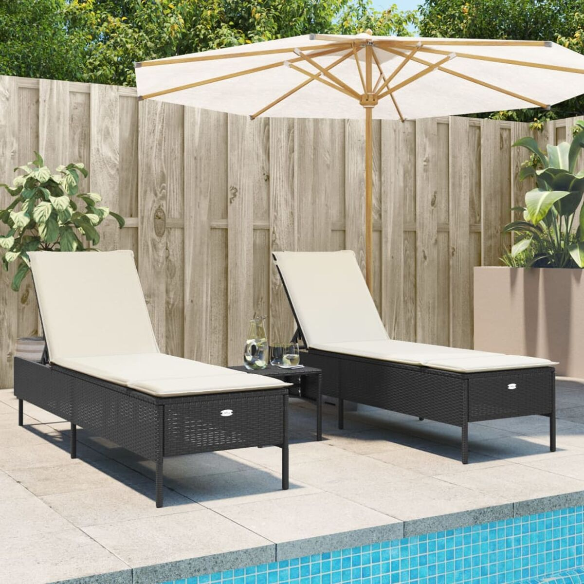 Zwei schwarze Chaiselongues mit Tisch und Sonnenschirm am Pool.