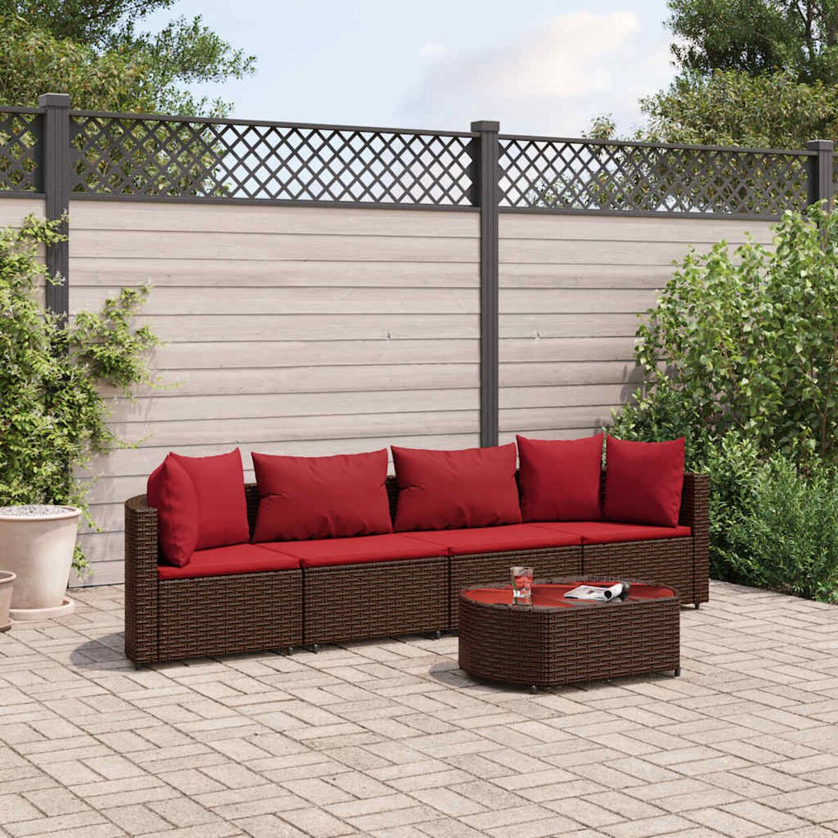 Rattan-Outdoormöbel-Set mit braunem Sofa und roten Kissen, mit einem braunen Tisch.