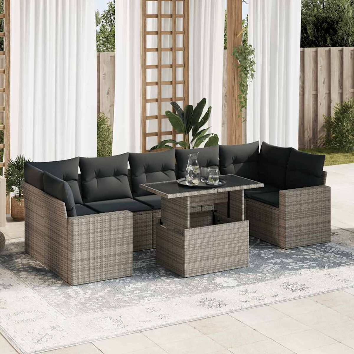 Set di mobili da patio con cuscini grigi. Ha un tavolo e divani, su un tappeto fantasia.