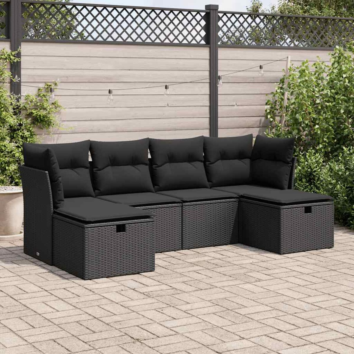 Ein schwarzes Outdoor-Ecksofa aus Korbgeflecht mit Kissen, auf einer Terrasse. Es hat Staufächer.