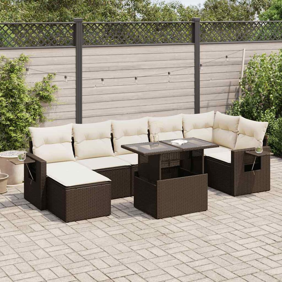 Outdoor-Sitzgruppe mit weißen Kissen und einem Tisch mit Glasplatte. Auf einer Terrasse mit erhöhtem Tisch.