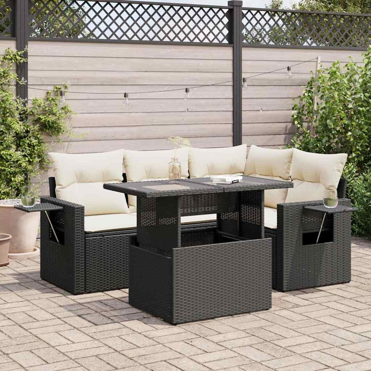 Set di mobili in vimini per esterni con cuscini neri. Include divano, tavolo e tavolini.