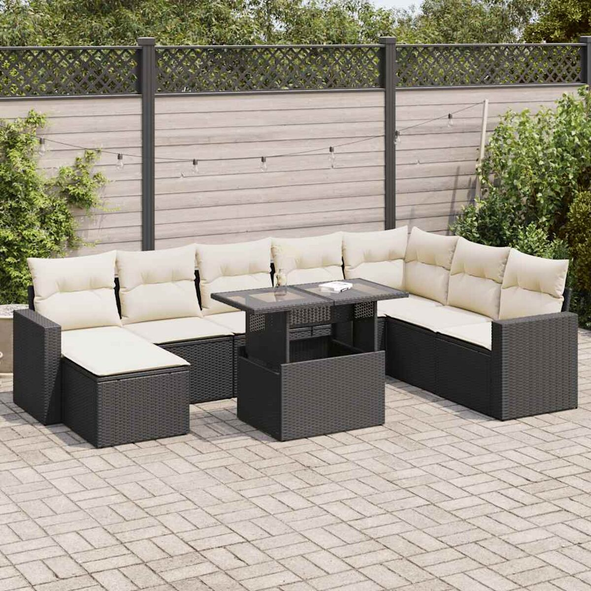 Divano componibile da esterno con vimini nero, cuscini beige e tavolo. Patio grigio.