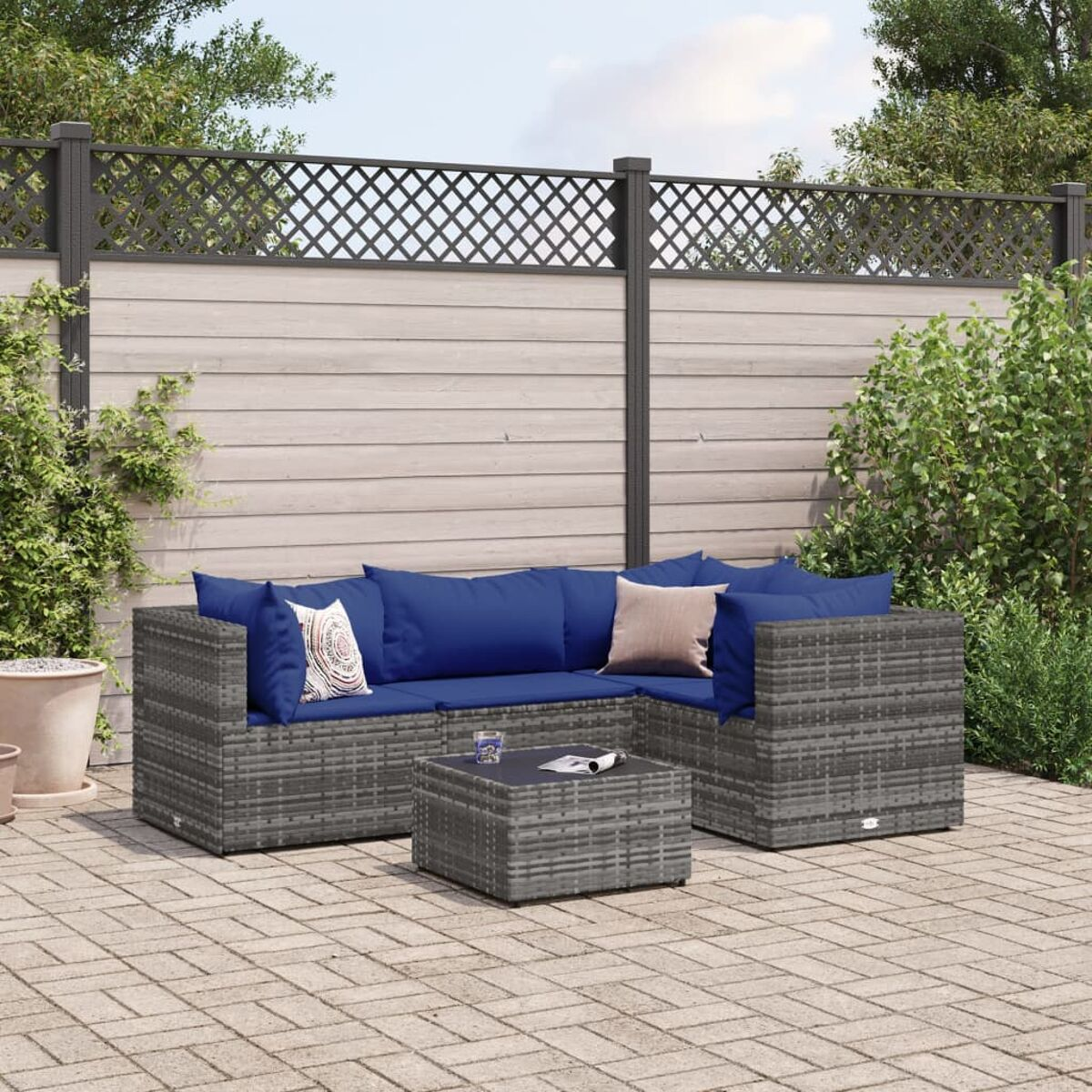 Graues Korbsessel-Outdoor-Set mit blauen Kissen, Tisch und Backsteinterrasse.