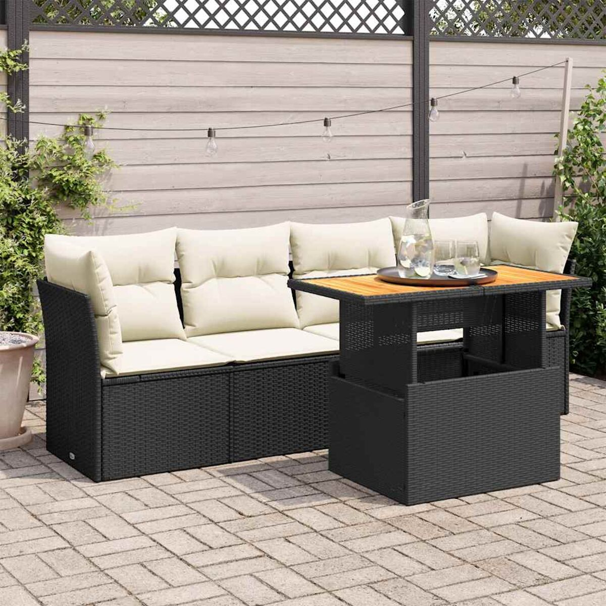 Set divano in rattan nero da esterno con cuscini beige e tavolo sollevabile.