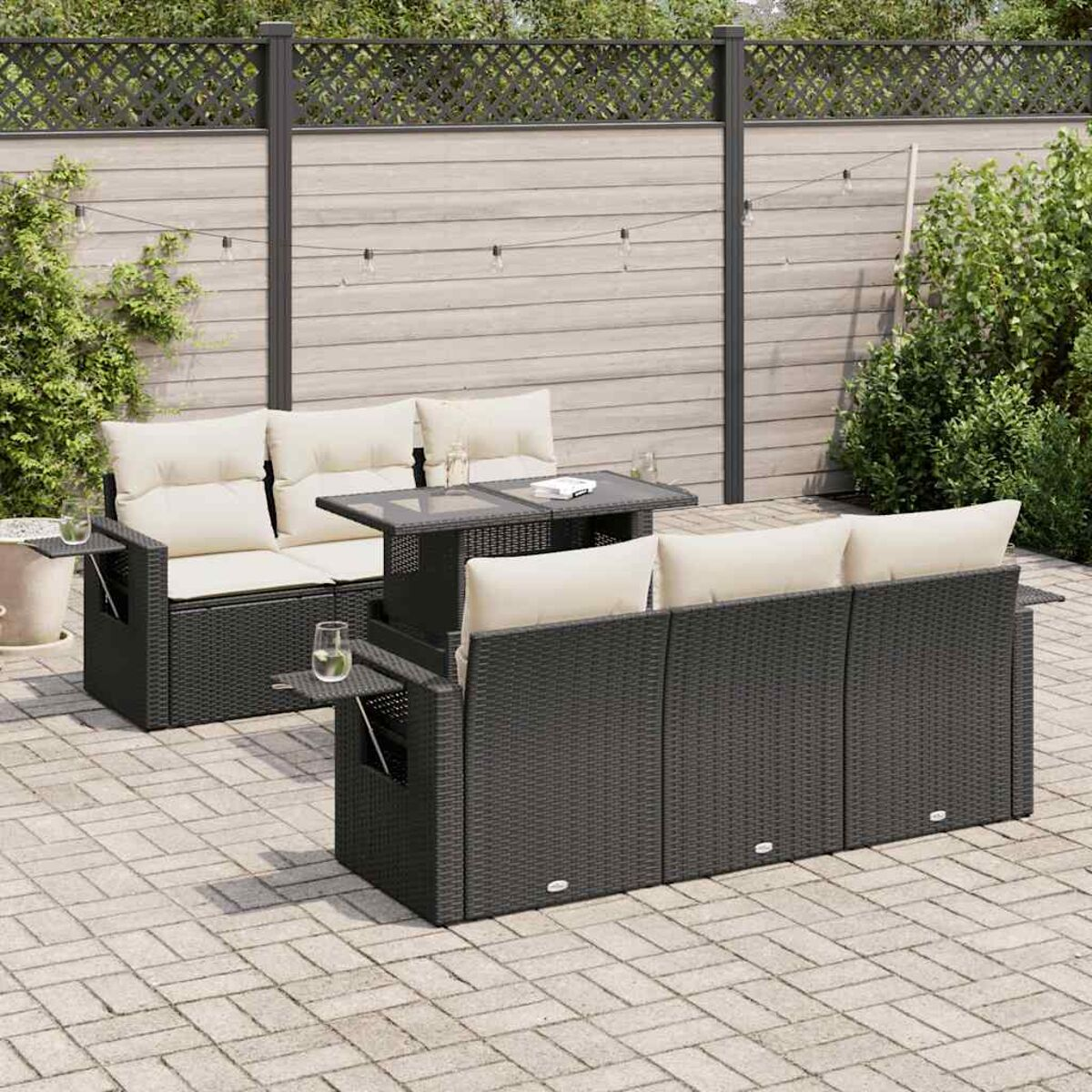 Set di mobili da esterno in rattan scuro con cuscini beige e tavolo alzabile. Ambientazione patio.