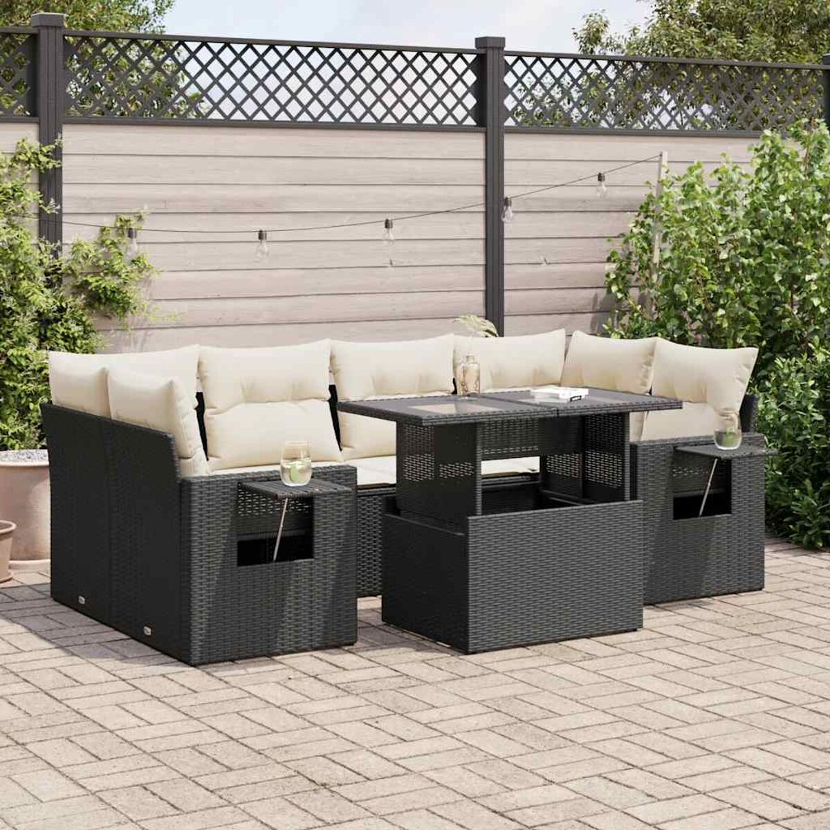 Un set di divani da esterno con struttura nera, cuscini beige e tavolo con piano in vetro.