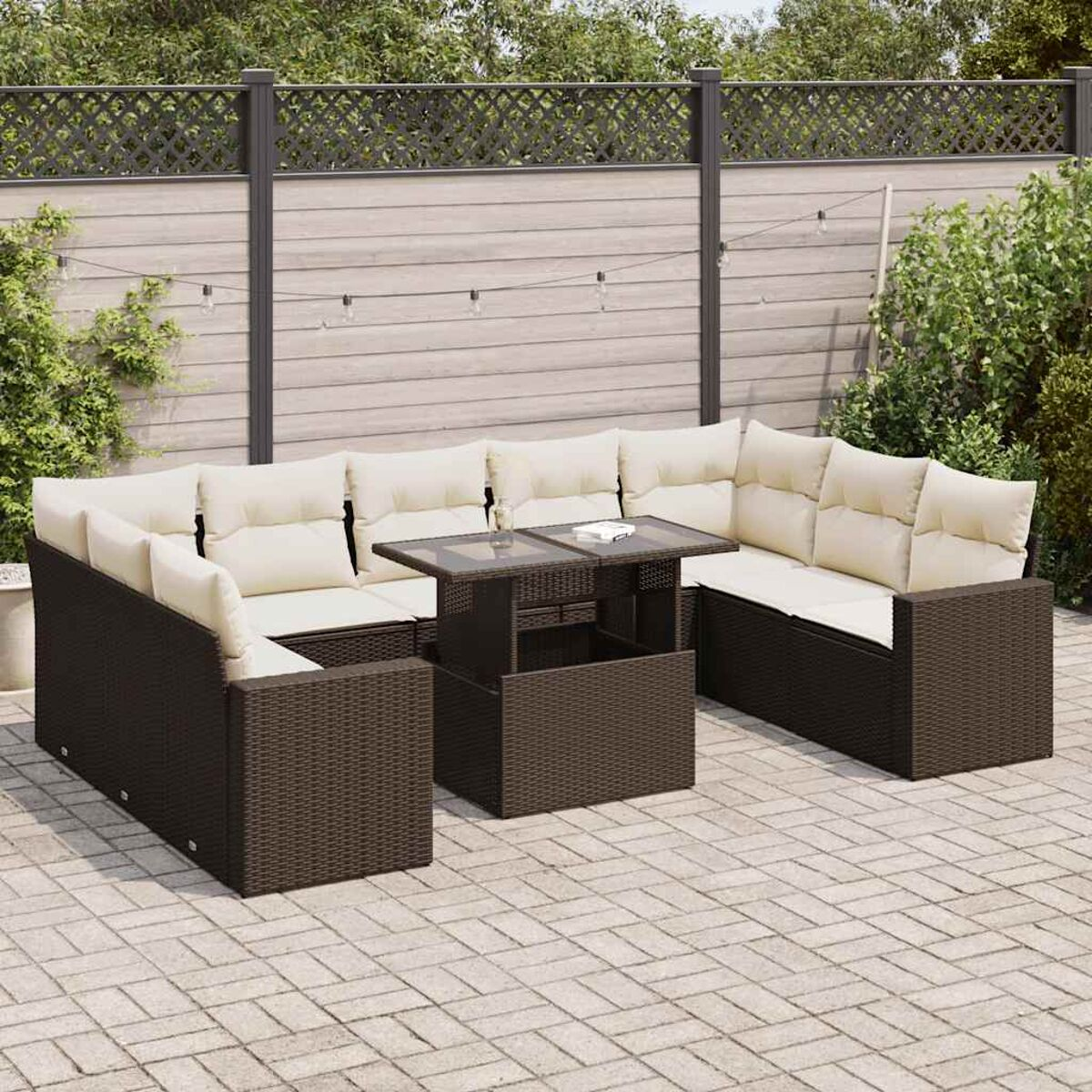 Dunkelbraunes Ecksofa aus Korbgeflecht mit Kissen und einem zentralen Tisch, auf einer Steinterrasse mit Grün.