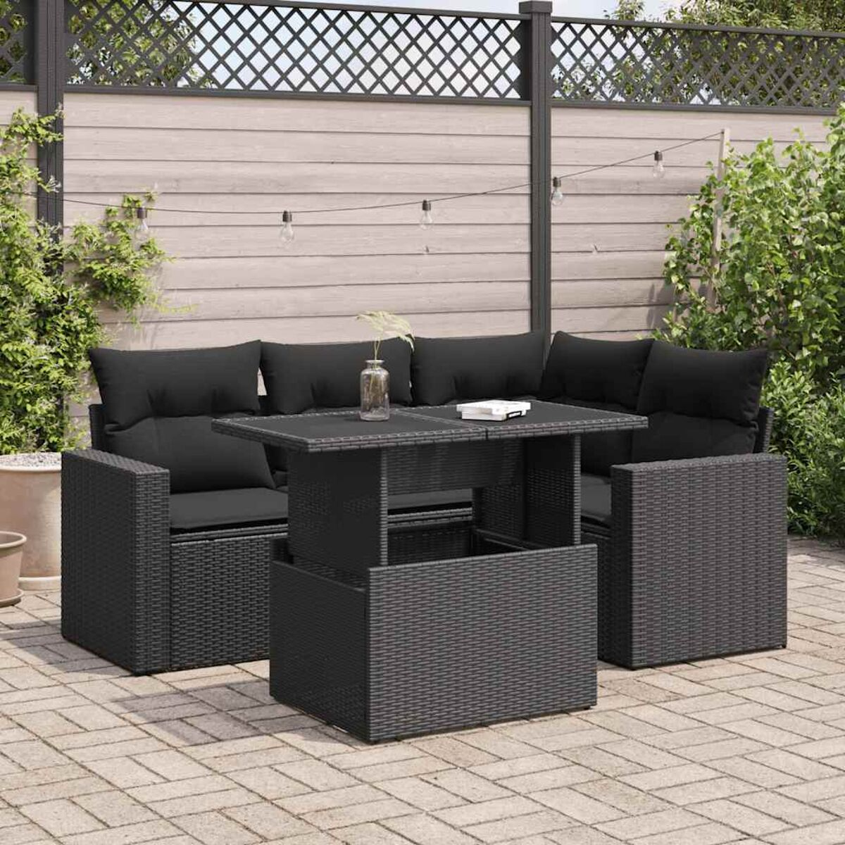 Set da patio in vimini nero. Include un divano, tavolo elevabile e due poltrone, su un patio.