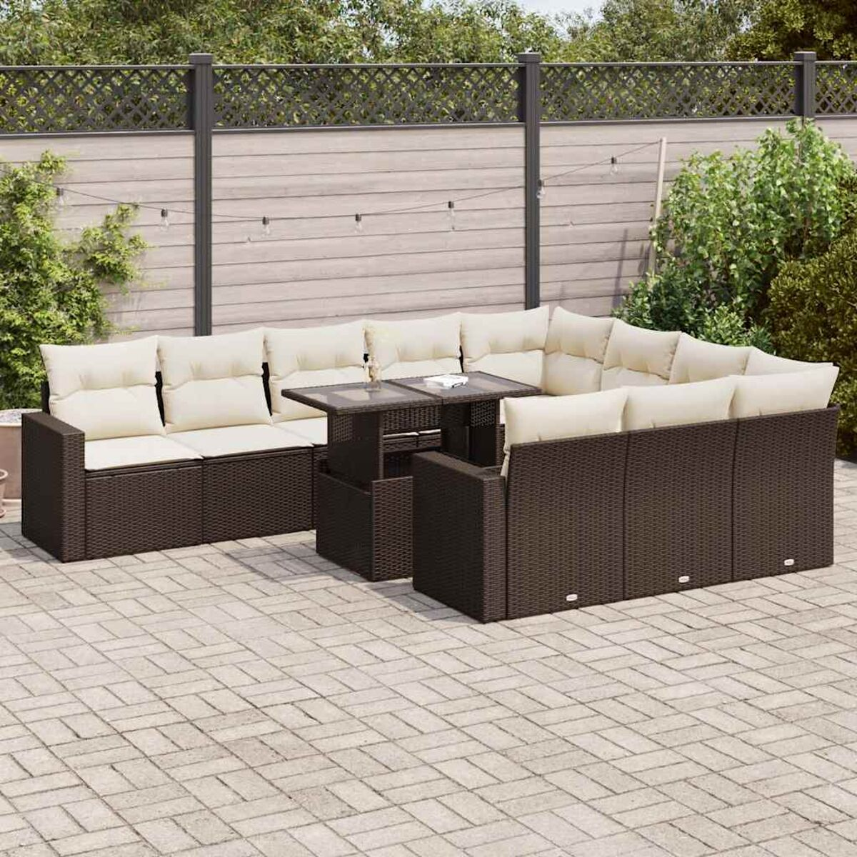 Outdoor-Rattan-Sofagarnitur mit Tisch, auf einer Stein-Terrasse, umgeben von Pflanzen.