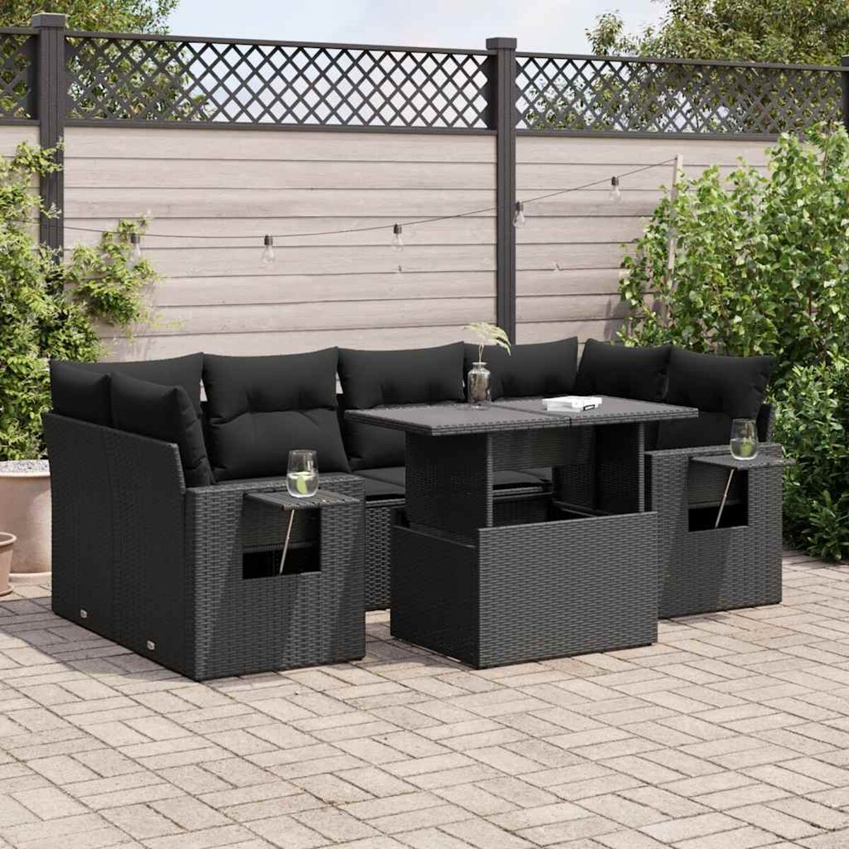 Set di mobili da esterno in vimini nero con cuscini e un tavolo, all'aperto con decorazioni.