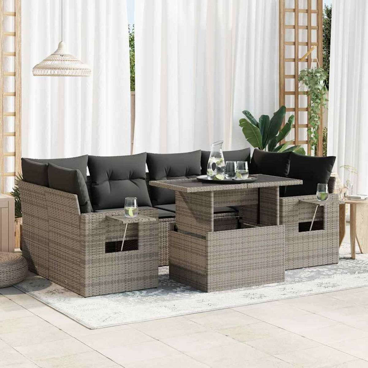 Set divano in rattan da esterno con tavolo, bicchieri e piante.
