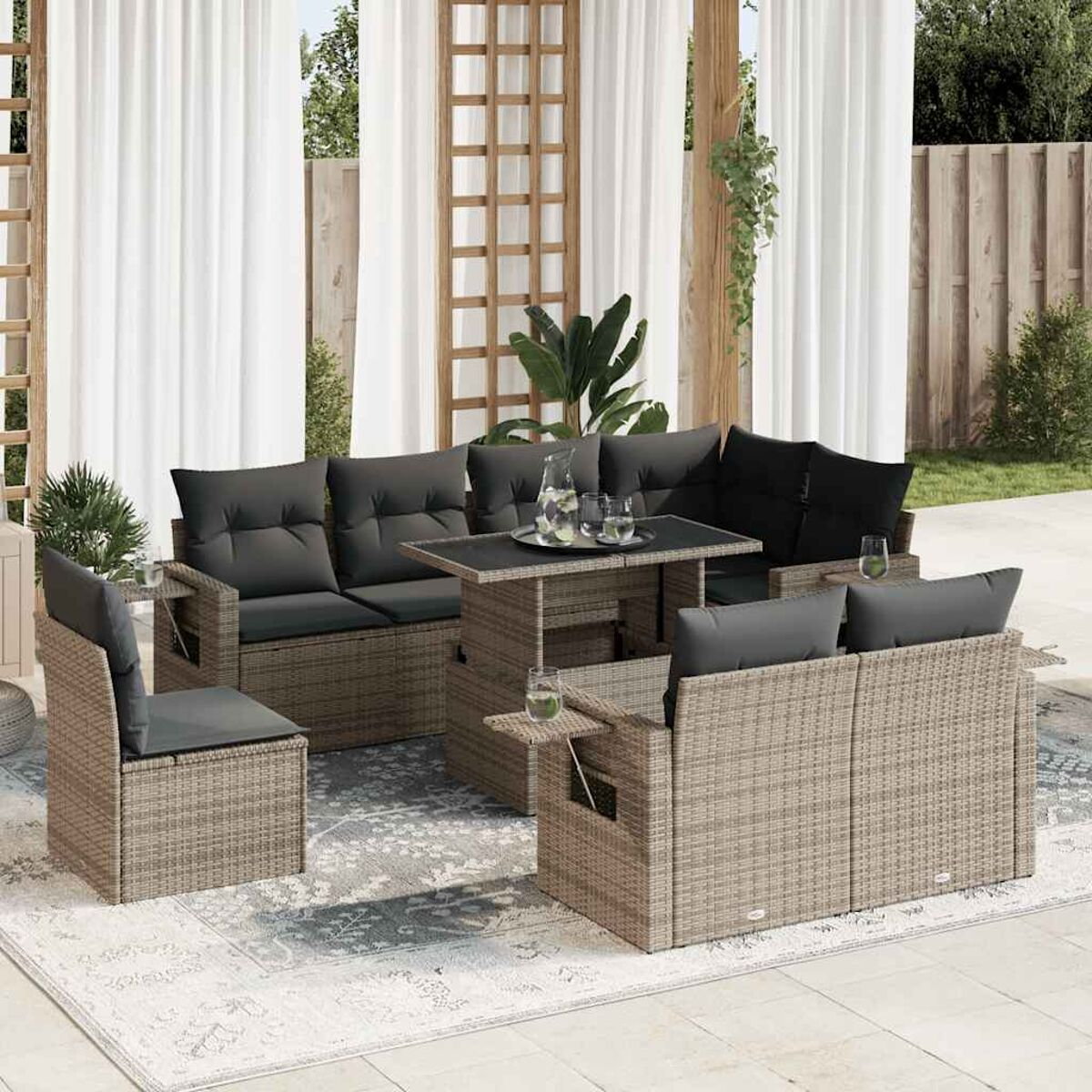 Geflochtenes Outdoor-Set mit grauen Kissen und einem Tisch. Pflanzen und Vorhänge im Hintergrund.