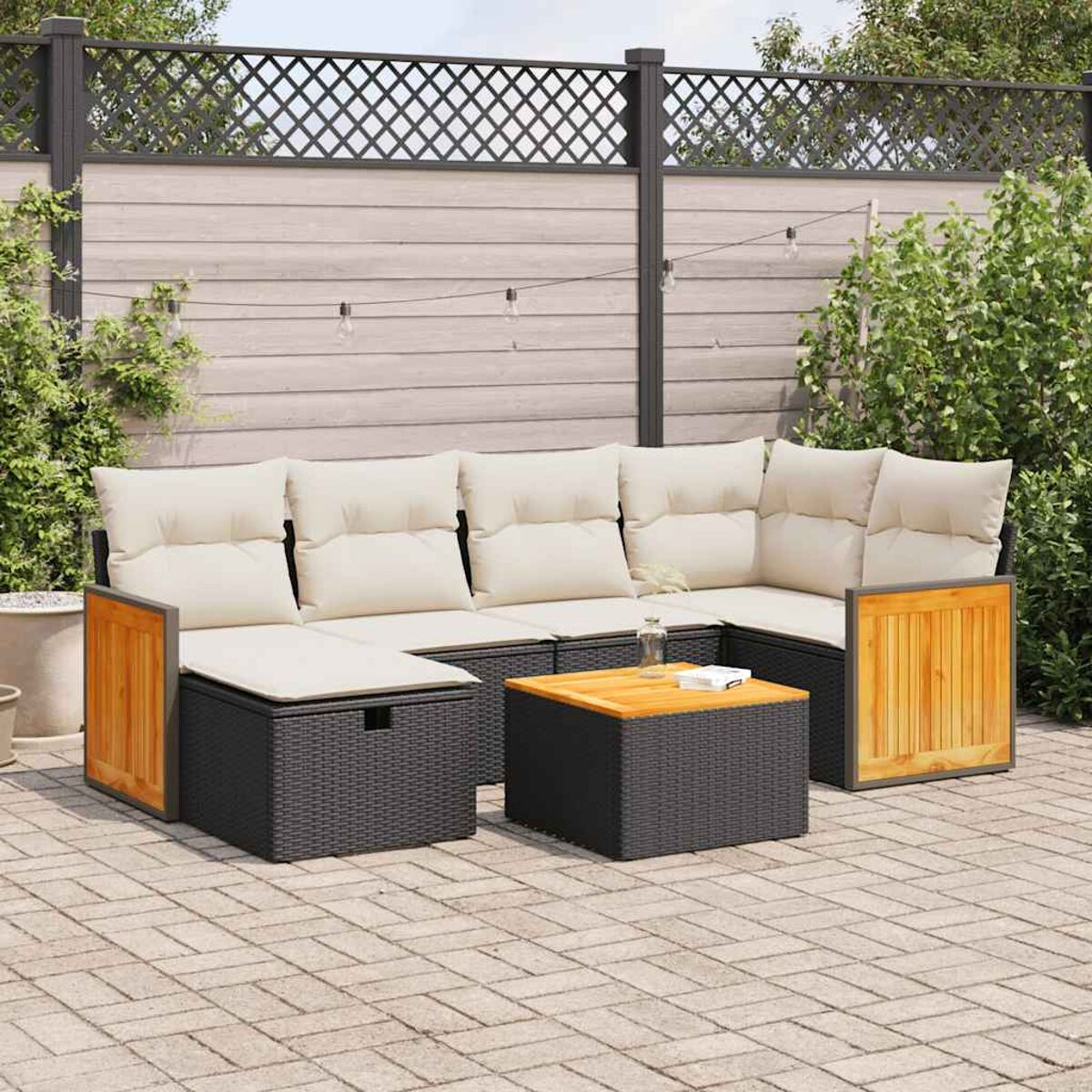 Gartensofa mit cremefarbenen Kissen, schwarzem Sockel und Holzakzenten auf einer Terrasse.