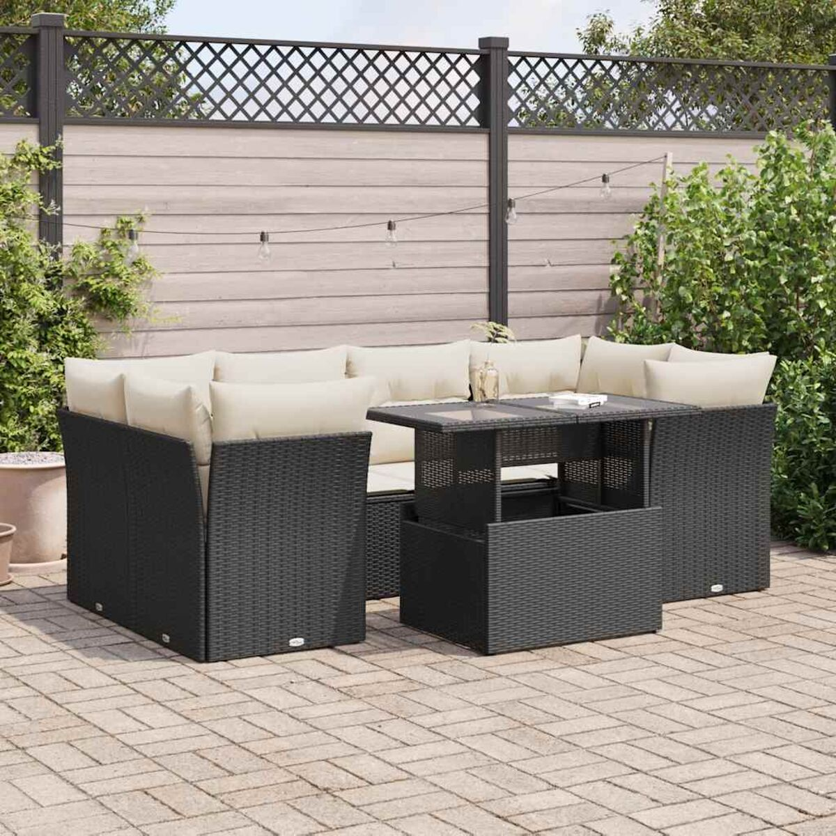 Set di mobili da esterno neri con cuscini beige e un tavolo su un patio in mattoni.