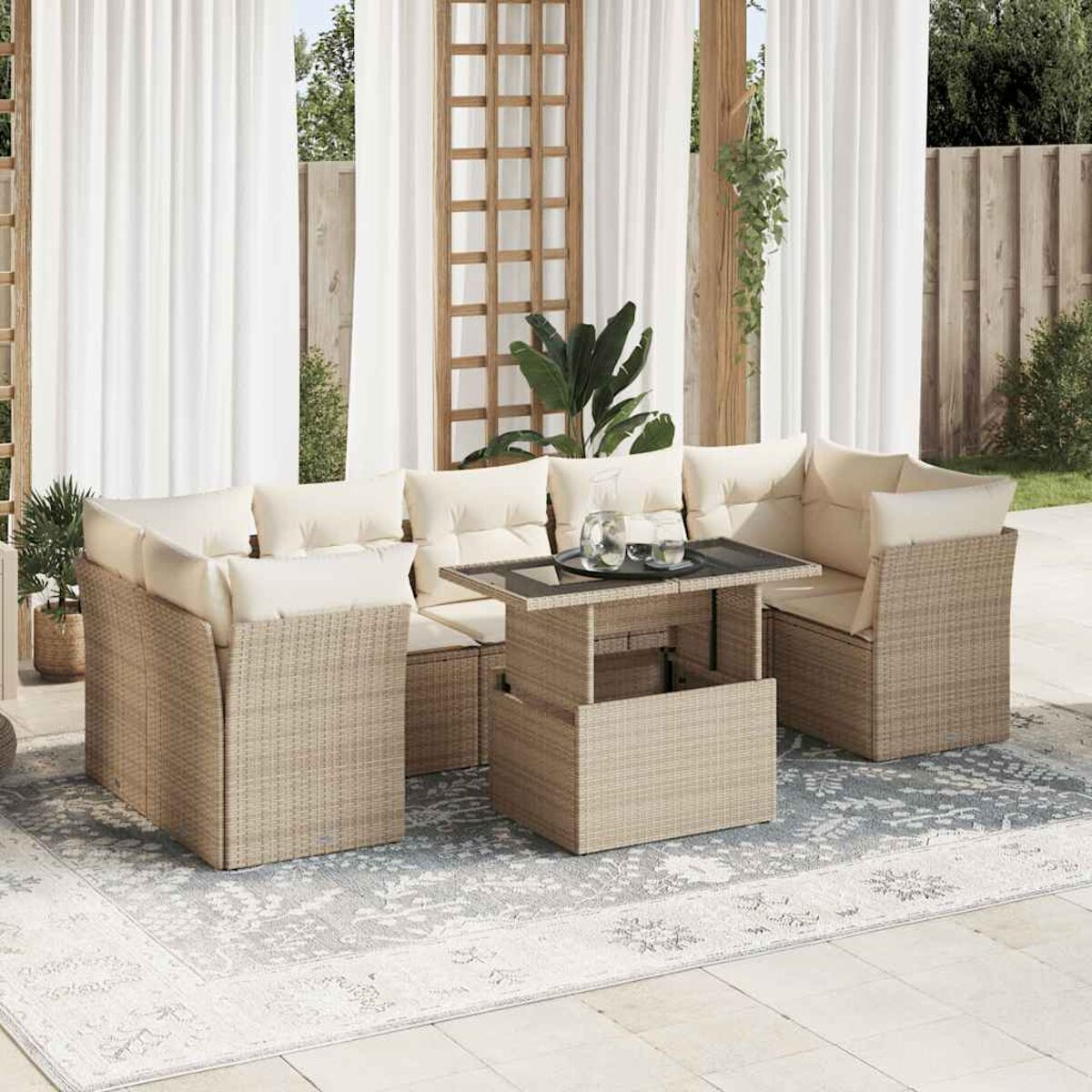 Set divano in rattan beige con cuscini color crema e un tavolo, su un tappeto fantasia.