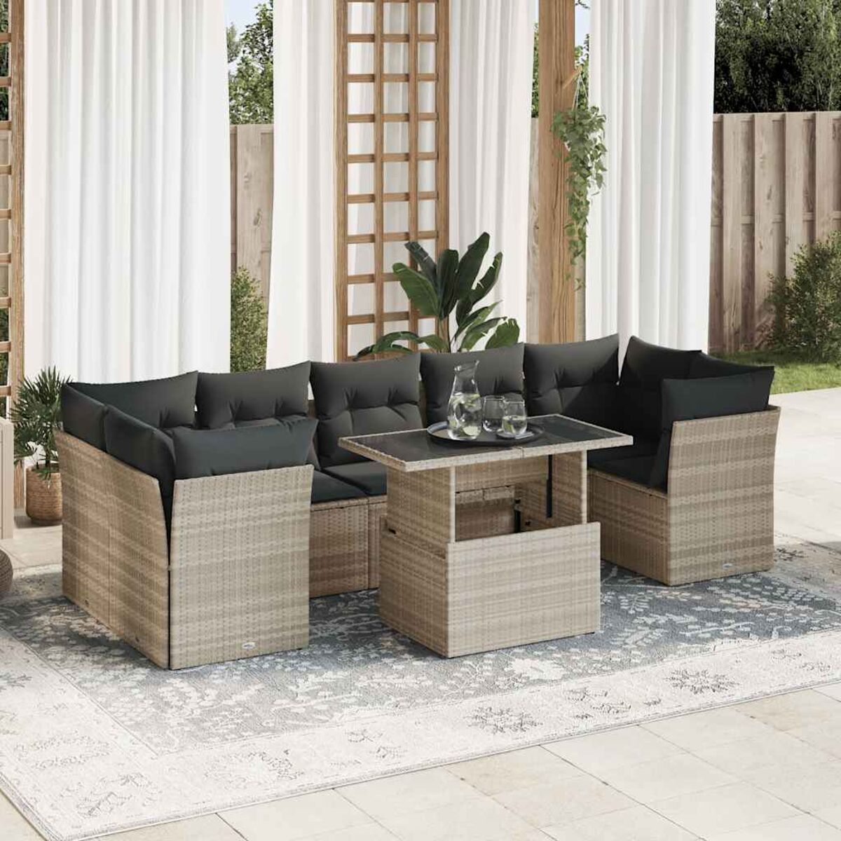 Divano in rattan con cuscini e tavolo. Tende bianche e patio.