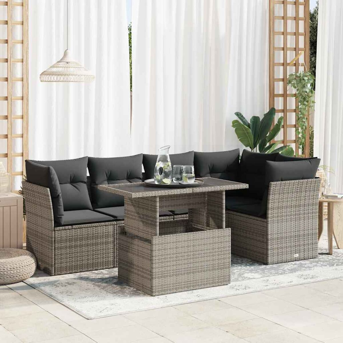 Divano in rattan con cuscini e tavolo. Tende bianche e patio.