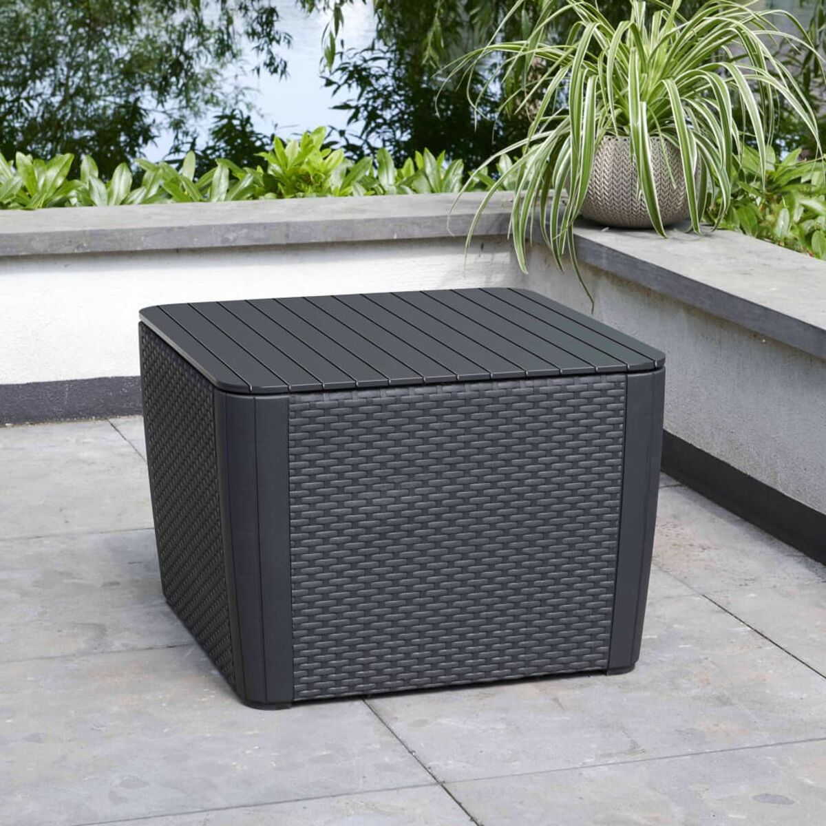 Un cubo contenitore in stile rattan grigio scuro con un piano grigio scuro. Su un patio.