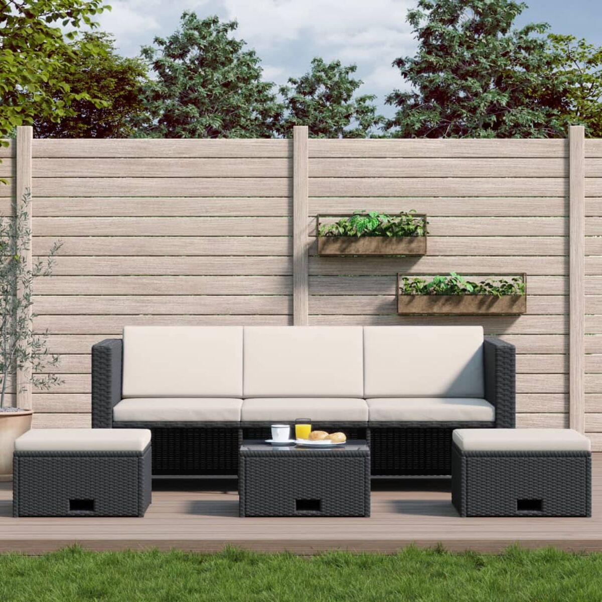Outdoor-Sofagarnitur. Schwarzes gewebtes Sofa, Ottomanen und Tisch mit Holzzaun im Hintergrund.