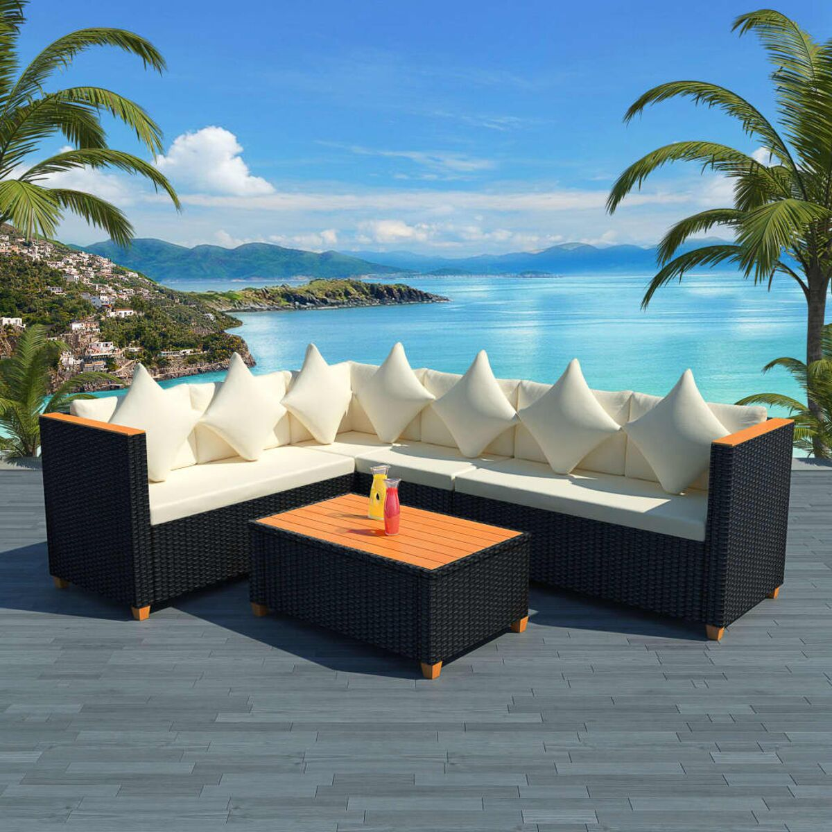 Gartenmöbelset mit Tisch, schwarzem Korbgeflecht, weißen Kissen und Meerblick.