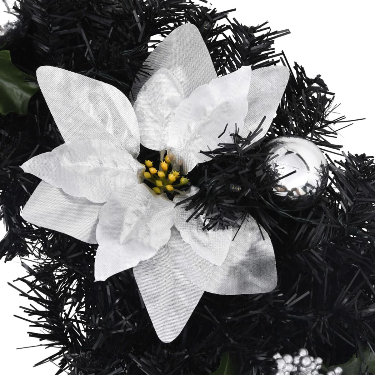 Nahaufnahme eines schwarzen Weihnachtskranzes mit weißem Weihnachtsstern und silbernen Ornamenten.