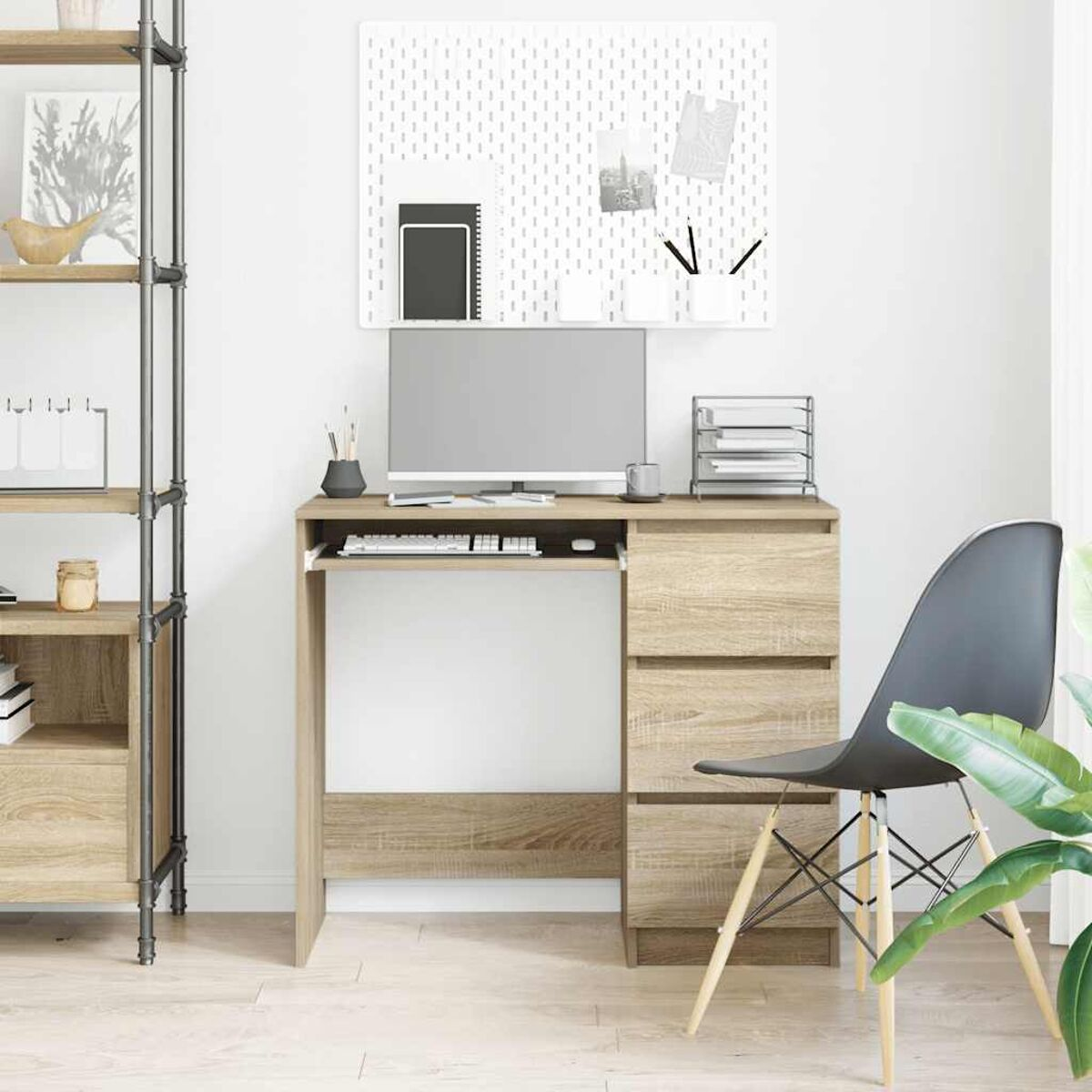 Ein Schreibtisch mit Computer, Schubladen und Stuhl. Eine Pinnwand an der Wand.