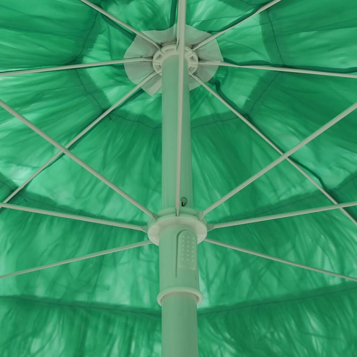Innenansicht eines grünen Regenschirms mit weißen Rippen und Mittelpfosten.
