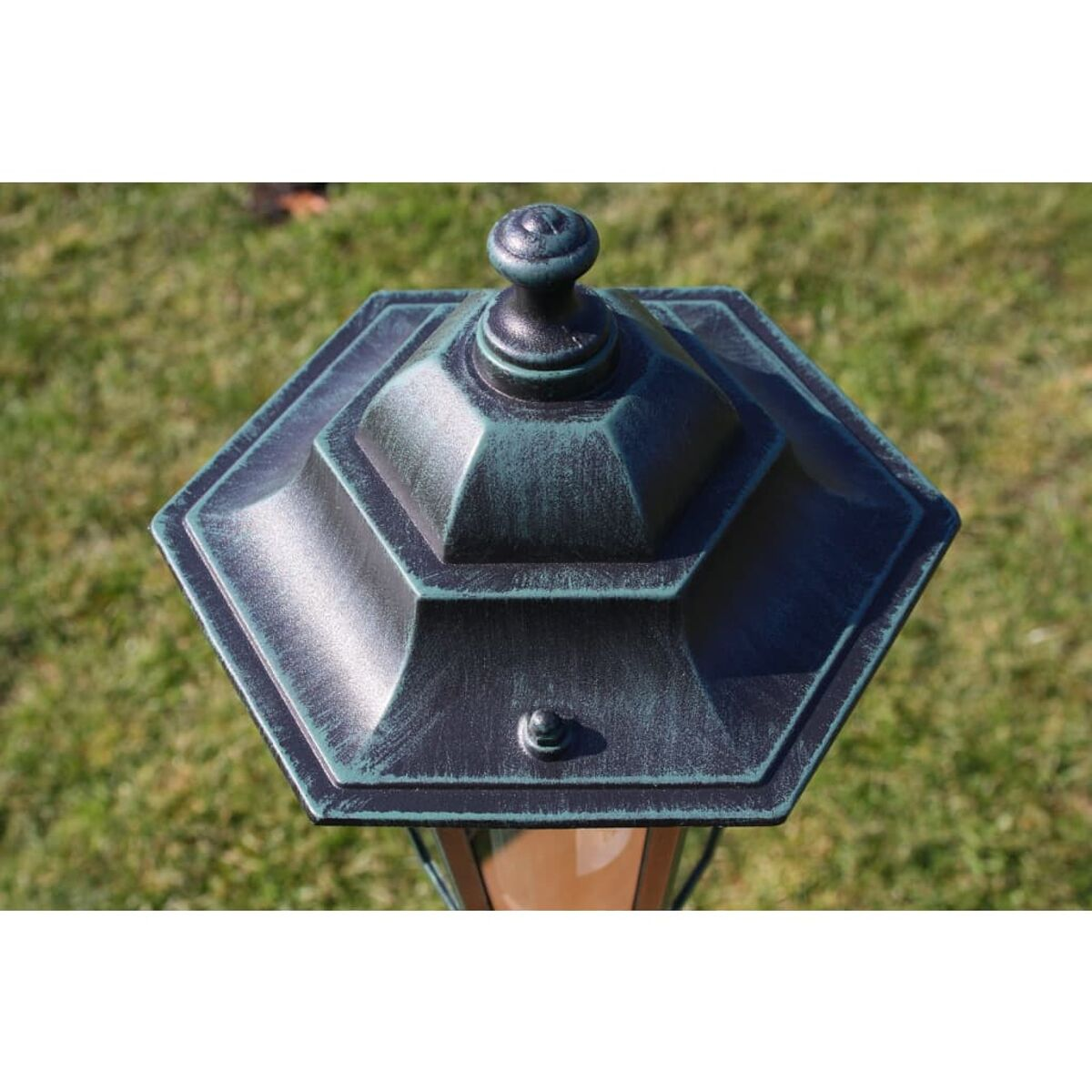 Eine sechseckige Außenlampe mit grüner Patina aus der Vogelperspektive.