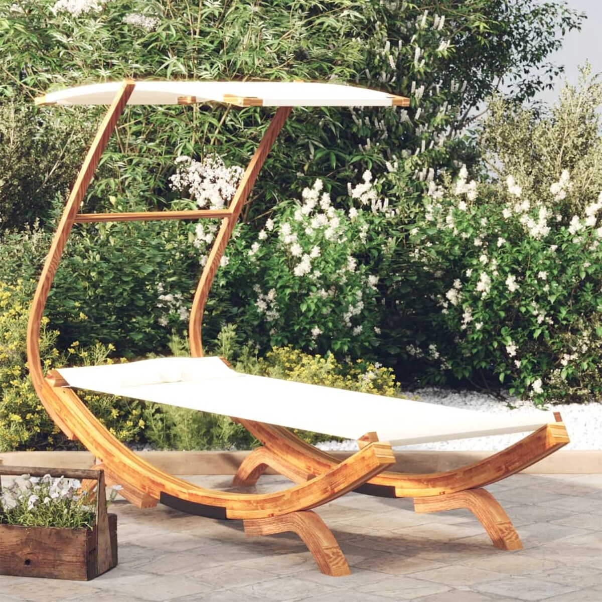 Ein hölzerner Outdoor-Liegestuhl mit weißem Verdeck, neben einem Blumenbeet und grünen Sträuchern.