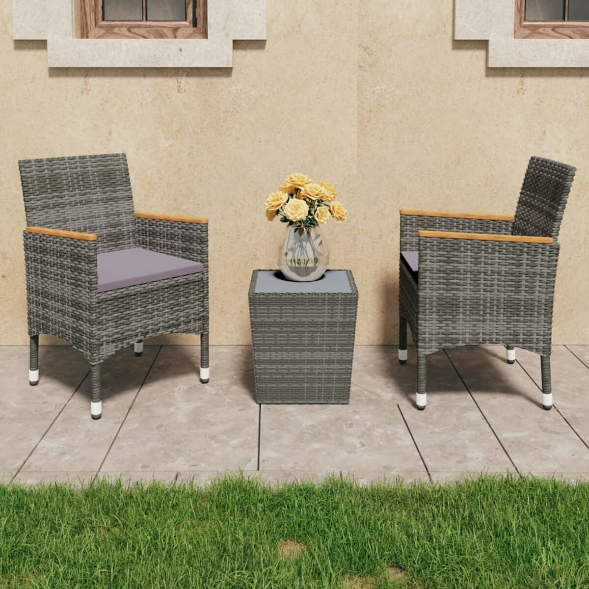 Zwei graue Korbstühle und ein kleiner Tisch mit Blumen stehen auf einer Terrasse mit Gras.