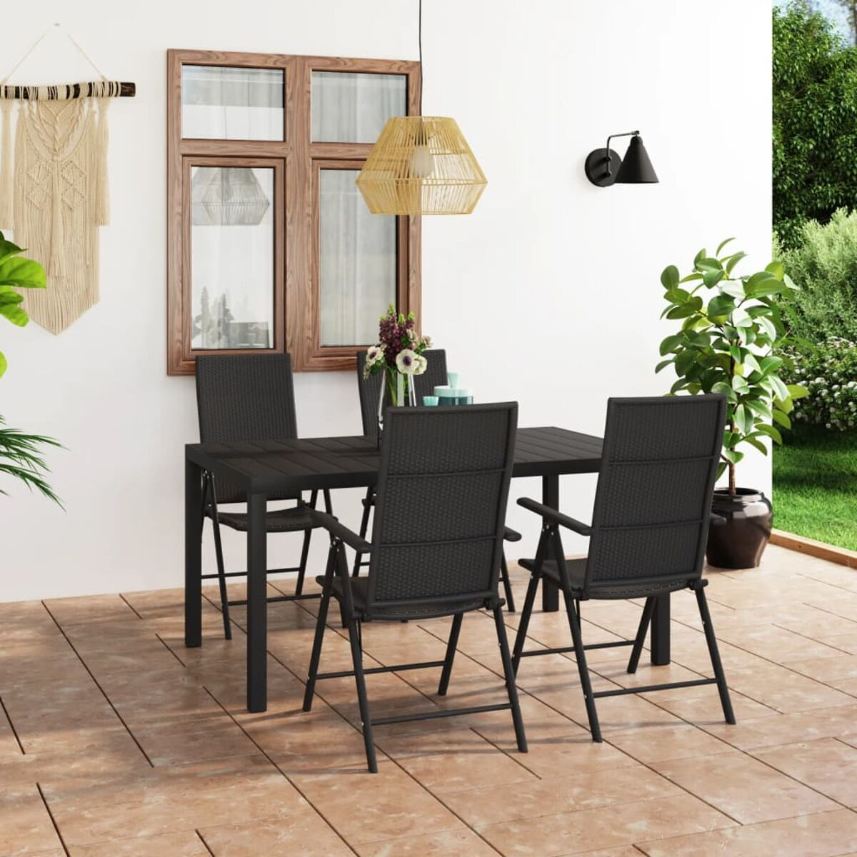 Terrassenset mit schwarzem Tisch, Stühlen und Dekoration.