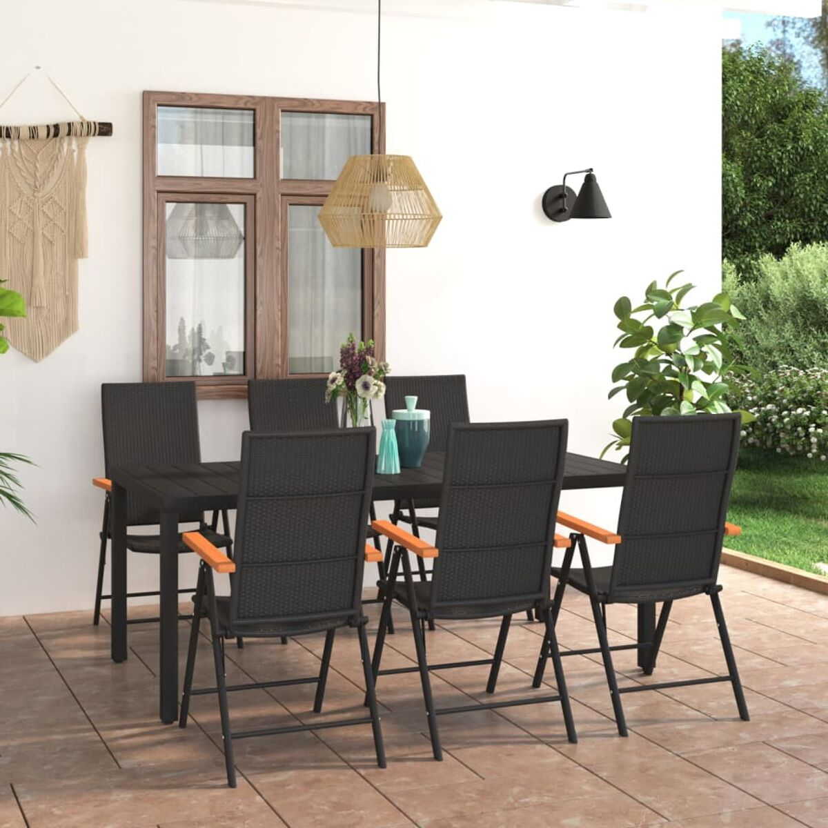Essgruppe im Freien. Schwarzer Tisch und Stühle auf einer Terrasse. Armlehnen aus Holz. Deko, Fenster und Pflanzen.
