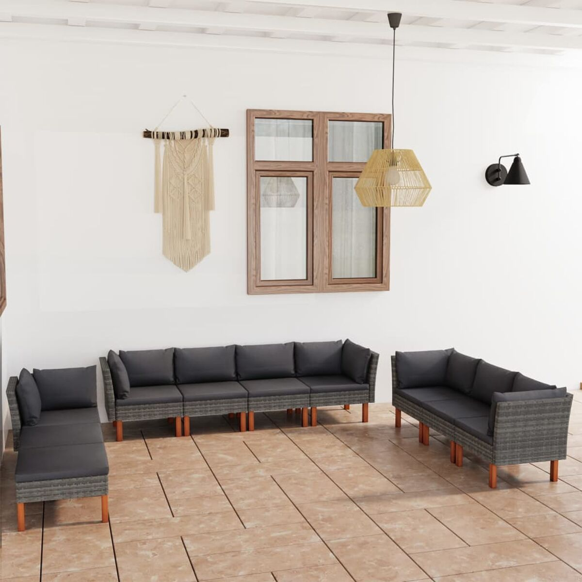 Terrassenmöbel-Set mit grauen Korbsesseln, Kissen und einem Makramee-Wandbehang.