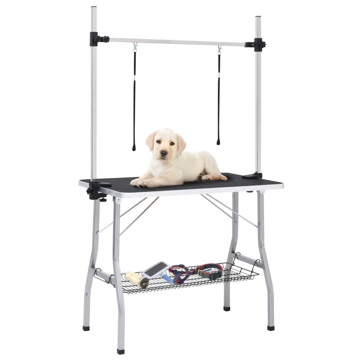 Ein Welpe liegt auf einem Pflegetisch. Der Tisch hat ein Metallgestell und eine schwarze Oberfläche.