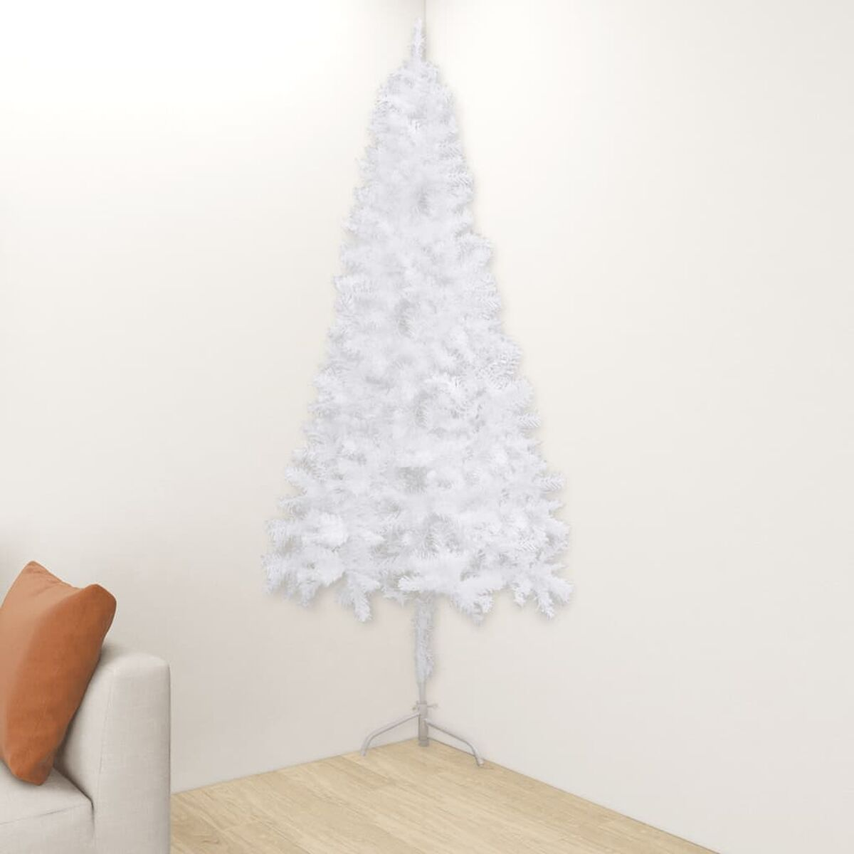 Ein weißer Weihnachtsbaum steht in einer Ecke. Links ist ein Sofa mit einem orangefarbenen Kissen.