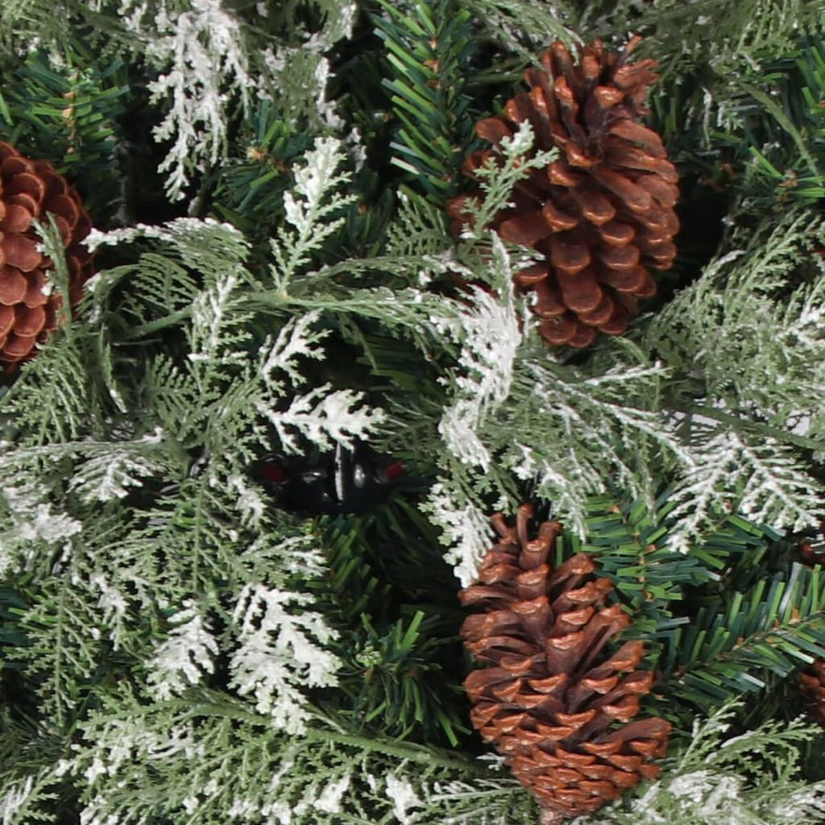 Nahaufnahme von Weihnachtsbaumzweigen mit braunen Tannenzapfen und schneeweissen Akzenten.