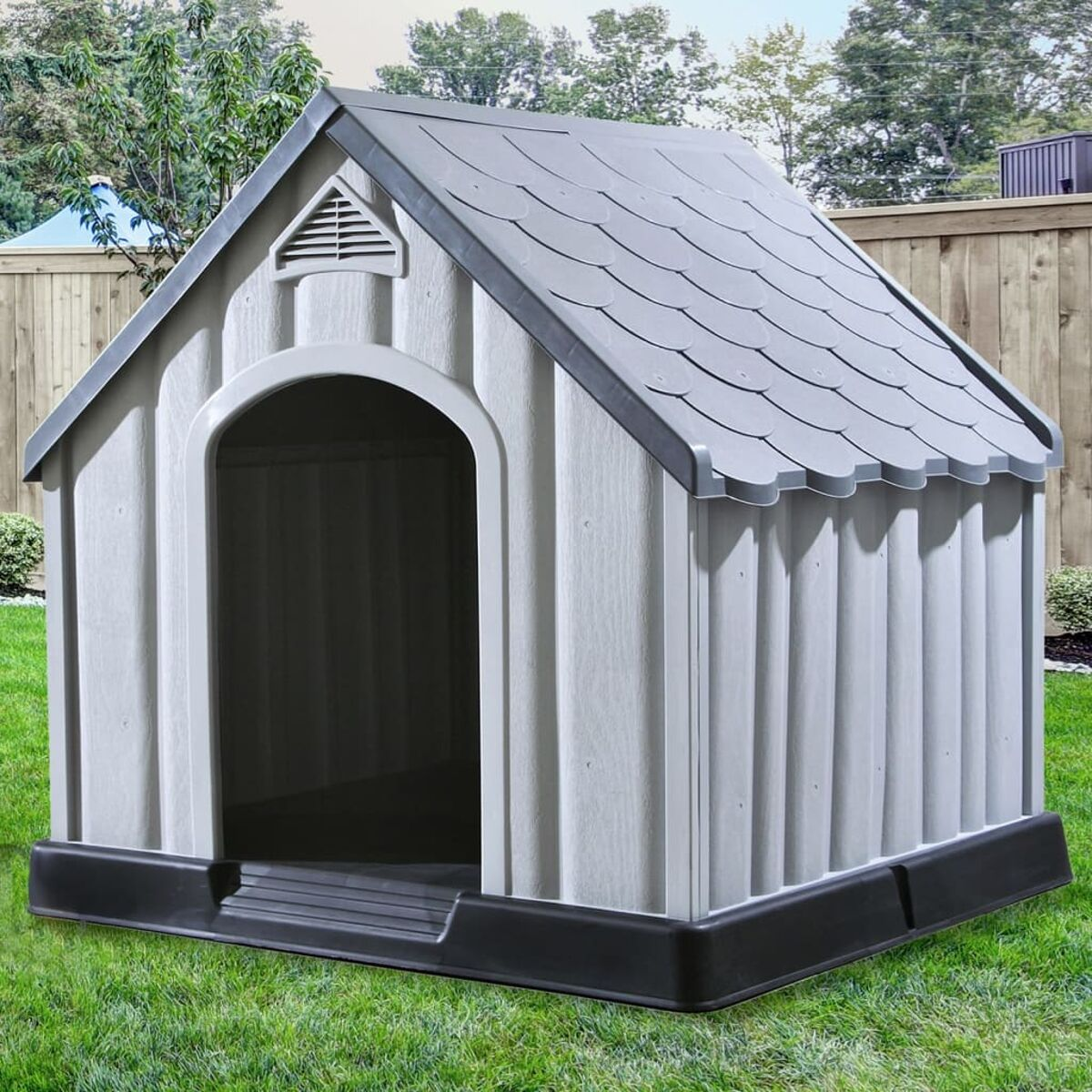 Ein Hundehütte mit grauem Dach und weißem Körper. Es steht auf Gras.